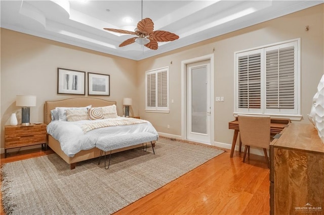 bedroom featuring ceiling fan, a tray ceiling, and light hardwood / wood-style flooring