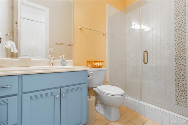 bathroom with vanity, hardwood / wood-style flooring, toilet, and an enclosed shower