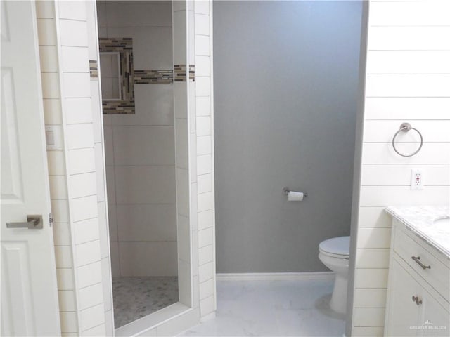 bathroom featuring a tile shower, vanity, and toilet