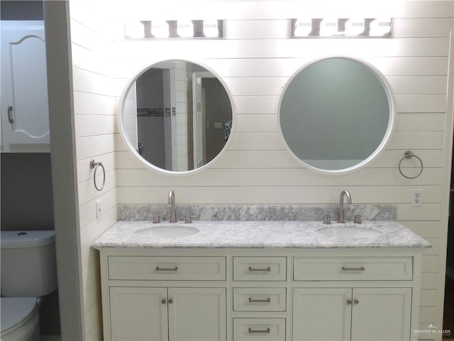 bathroom featuring wooden walls, vanity, and toilet