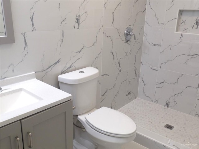 bathroom with a shower, vanity, tile walls, and toilet