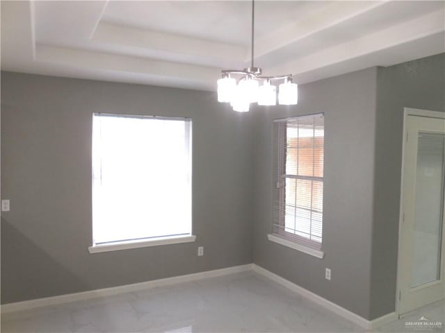 empty room with a tray ceiling, a healthy amount of sunlight, and a notable chandelier