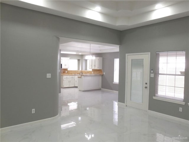 unfurnished living room with a raised ceiling and a chandelier