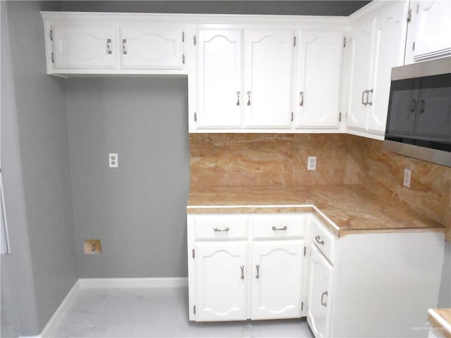 kitchen featuring white cabinets, light tile patterned floors, and tasteful backsplash