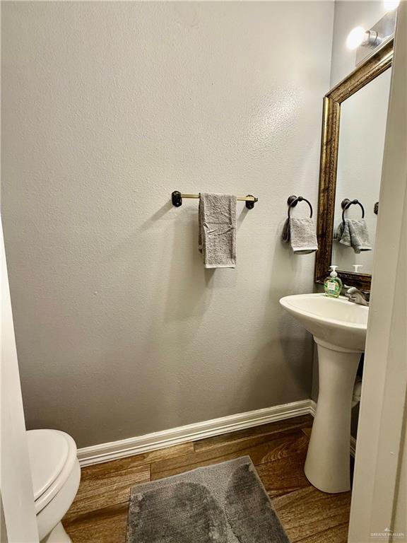 3100 Princeton Ave, Mcallen, TX 78504 - half bathroom with baseboards, wood finished floors, and toilet