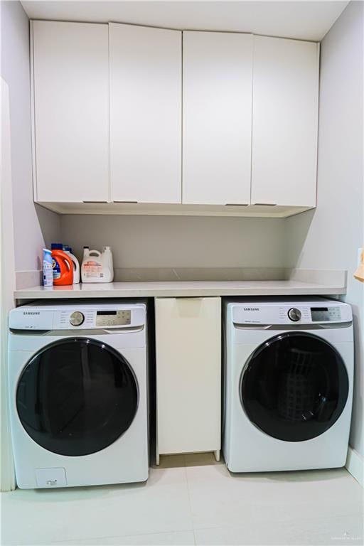 clothes washing area with light tile patterned flooring, cabinets, and separate washer and dryer