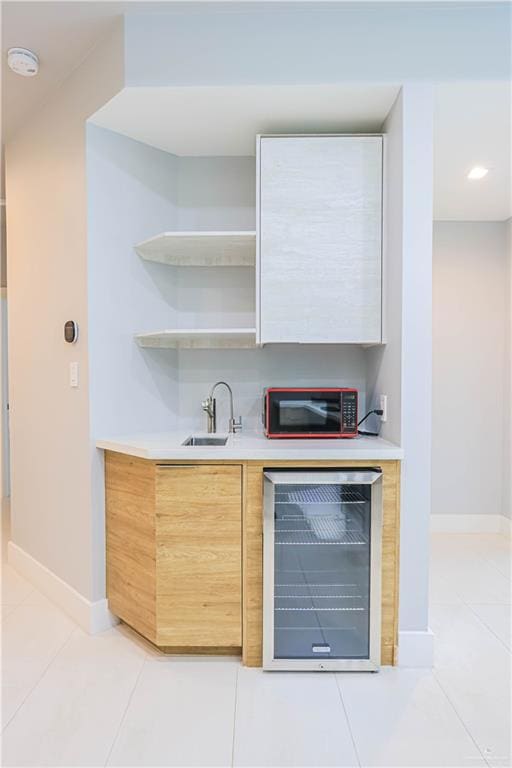 bar featuring light tile patterned floors, beverage cooler, and sink