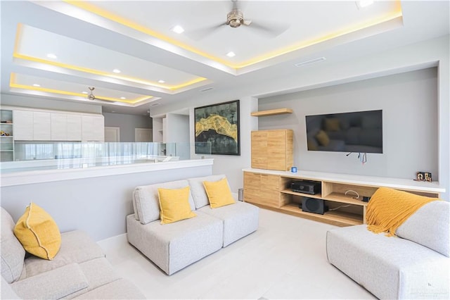 living room featuring ceiling fan and a tray ceiling