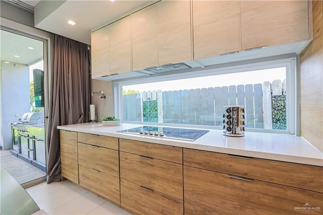 kitchen with stovetop, light tile patterned floors, and a healthy amount of sunlight