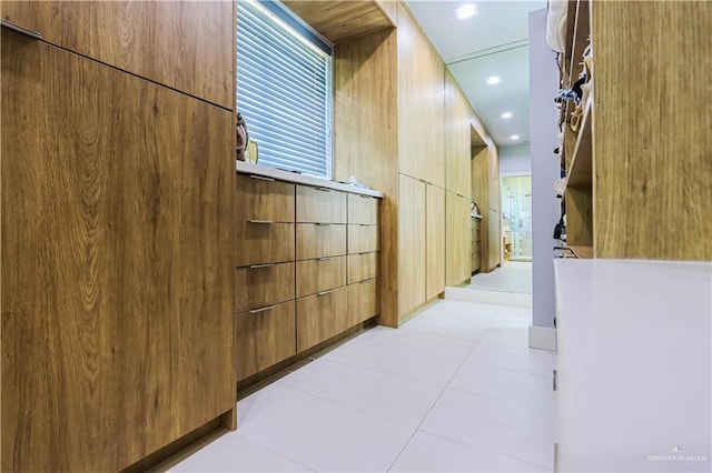 corridor with light tile patterned floors and wood walls