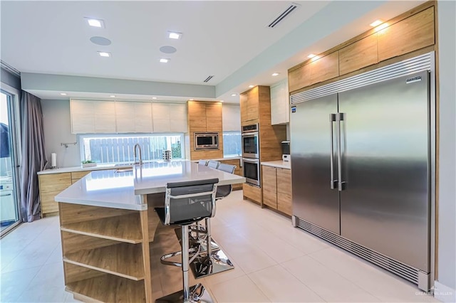 kitchen featuring a kitchen bar, built in appliances, and a kitchen island