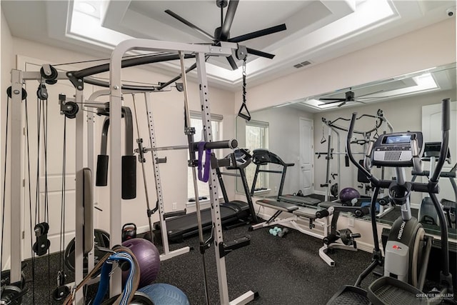 workout area featuring ceiling fan and a tray ceiling