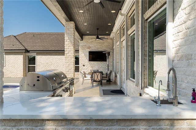 view of patio featuring ceiling fan, area for grilling, sink, and grilling area