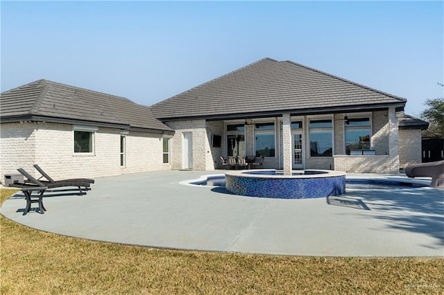 rear view of property featuring a pool with hot tub and a patio area