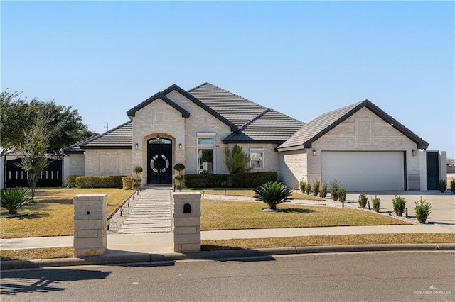 french country inspired facade featuring a garage and a front yard