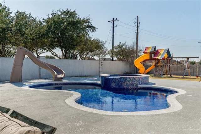 view of swimming pool featuring a playground, an in ground hot tub, a water slide, and a patio area