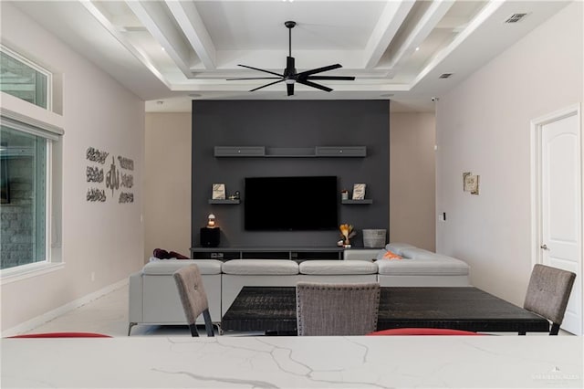 living room featuring ceiling fan and a raised ceiling