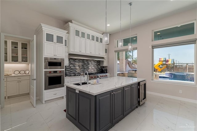 kitchen with sink, white cabinets, beverage cooler, decorative backsplash, and hanging light fixtures