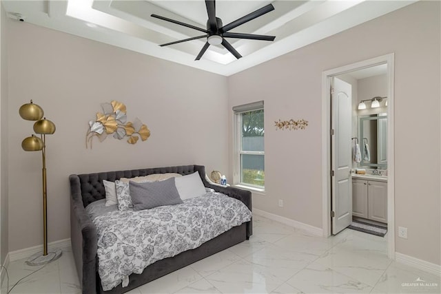 bedroom featuring a raised ceiling, ceiling fan, sink, and ensuite bath