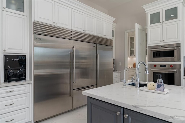 kitchen featuring light stone counters, sink, white cabinets, and appliances with stainless steel finishes