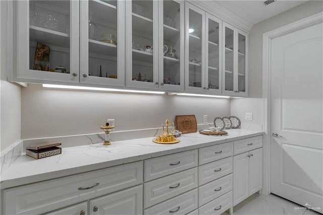 bar featuring light stone counters and white cabinets