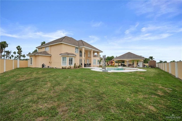 rear view of property with a lawn, a fenced backyard, a gazebo, and an outdoor pool