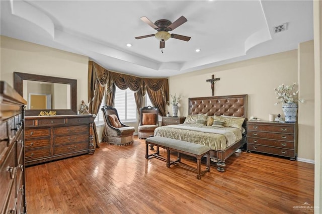bedroom with visible vents, recessed lighting, wood finished floors, ceiling fan, and a raised ceiling