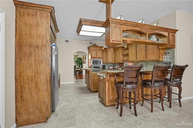 kitchen with arched walkways, baseboards, a peninsula, tasteful backsplash, and appliances with stainless steel finishes