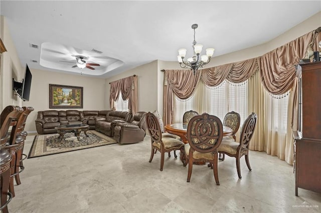 dining area with ceiling fan with notable chandelier, visible vents, and a tray ceiling