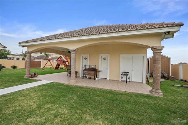 back of property featuring a tile roof, a patio, a playground, and fence