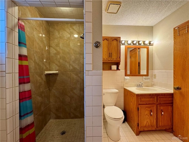 full bathroom with toilet, wainscoting, a tile shower, and tile walls