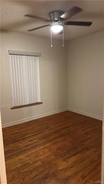 unfurnished room featuring dark wood-type flooring, a textured ceiling, baseboards, and a ceiling fan