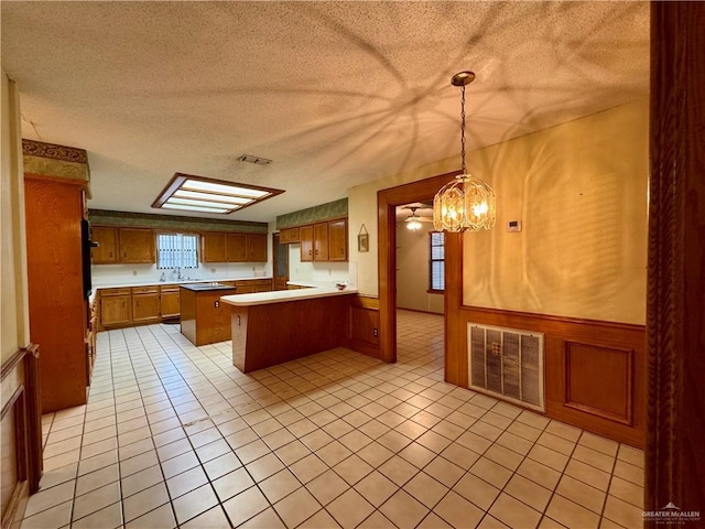 kitchen featuring brown cabinets, visible vents, pendant lighting, and light countertops