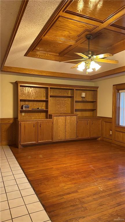 unfurnished living room featuring wooden ceiling, light wood-style flooring, and a wainscoted wall