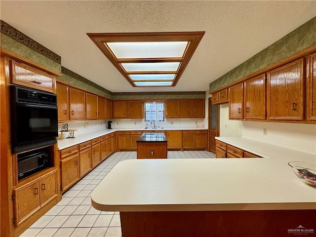 kitchen with a center island, brown cabinets, light countertops, and black oven