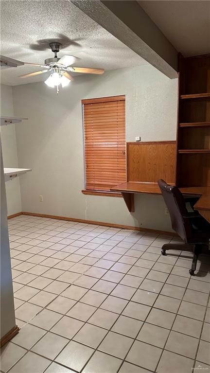 unfurnished office with built in features, light tile patterned floors, a ceiling fan, a textured ceiling, and wooden walls