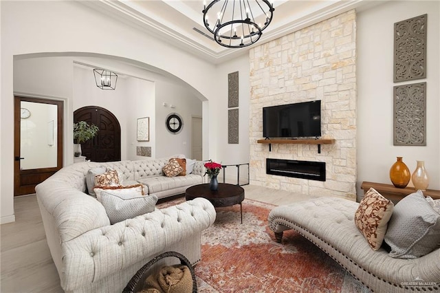 living room featuring an inviting chandelier, arched walkways, a fireplace, and wood finished floors