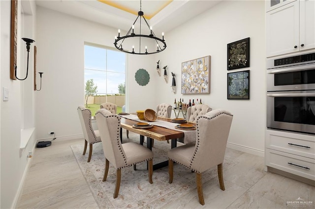 dining room with baseboards, a tray ceiling, and a notable chandelier