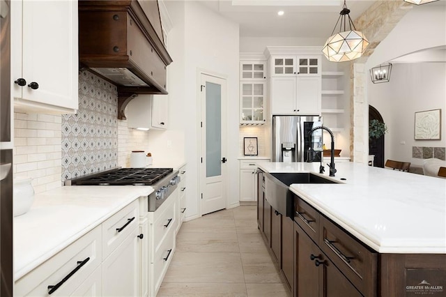kitchen featuring dark brown cabinets, range hood, light countertops, arched walkways, and stainless steel appliances