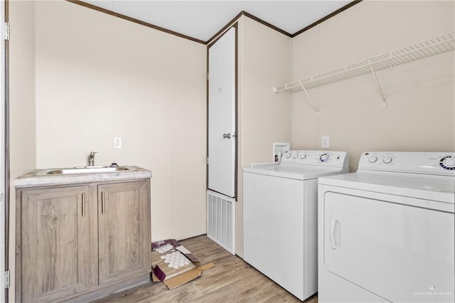 washroom featuring separate washer and dryer, crown molding, light hardwood / wood-style floors, and sink