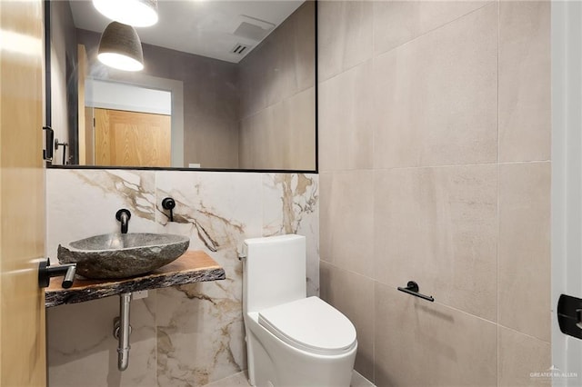 bathroom featuring backsplash, toilet, tile walls, and sink