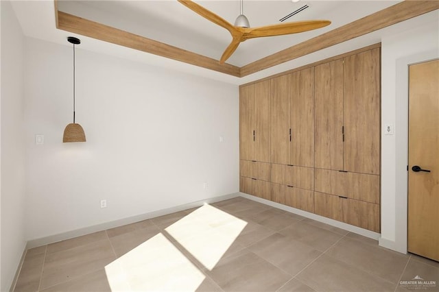 tiled spare room with ceiling fan and a tray ceiling