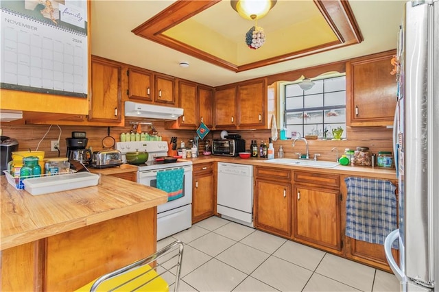 kitchen with tasteful backsplash, white appliances, sink, light tile patterned floors, and butcher block countertops