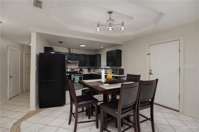 tiled dining area featuring a tray ceiling and sink