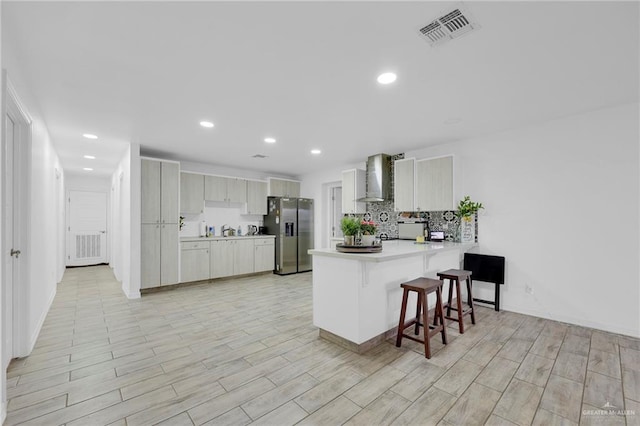 117 W Hawk Ave, Pharr, TX 78577 - kitchen featuring stainless steel fridge, wall chimney exhaust hood, a peninsula, a breakfast bar, and light countertops