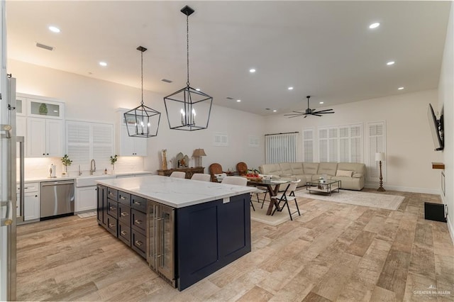 kitchen featuring white cabinetry, a center island, hanging light fixtures, stainless steel dishwasher, and light stone countertops