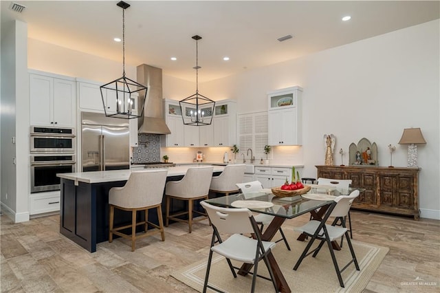 kitchen featuring appliances with stainless steel finishes, backsplash, white cabinets, a kitchen island, and wall chimney exhaust hood