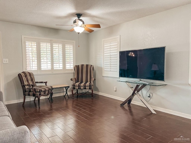 living area featuring ceiling fan, dark hardwood / wood-style flooring, and a textured ceiling