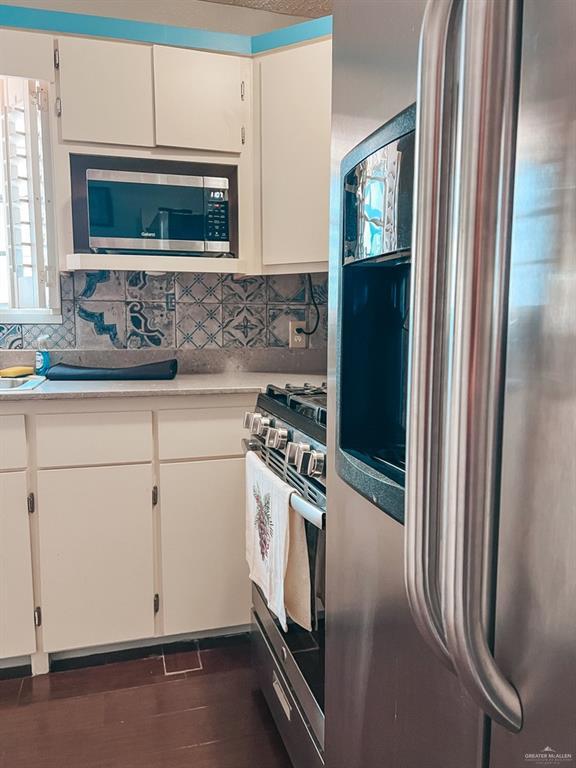 kitchen featuring tasteful backsplash, dark hardwood / wood-style flooring, white cabinets, and stainless steel appliances