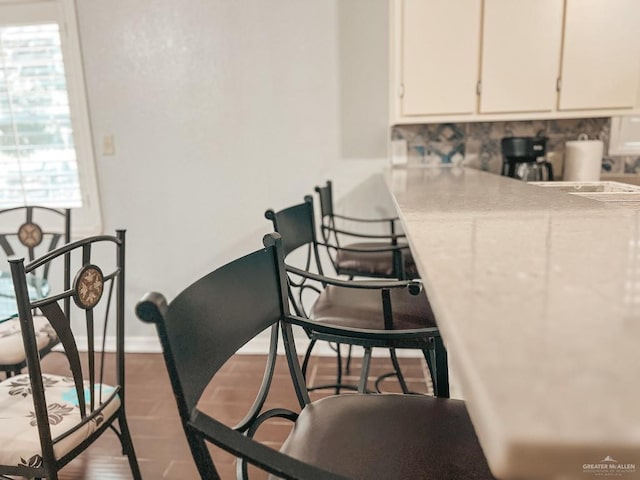 kitchen with tasteful backsplash, white cabinetry, a healthy amount of sunlight, and hardwood / wood-style flooring